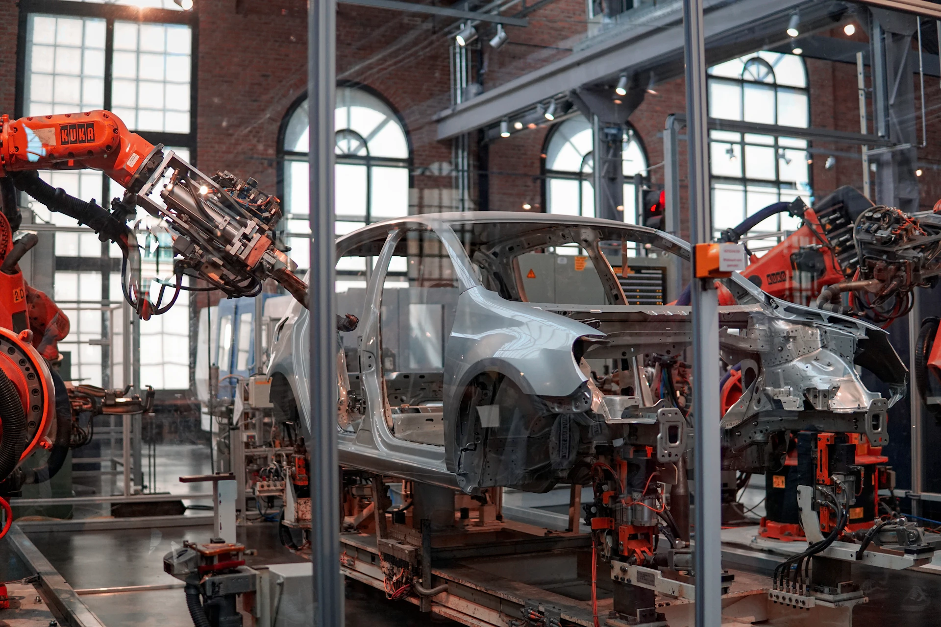 Automatización en planta de automóviles Carrocería gris rodeada por robots en una planta automotriz