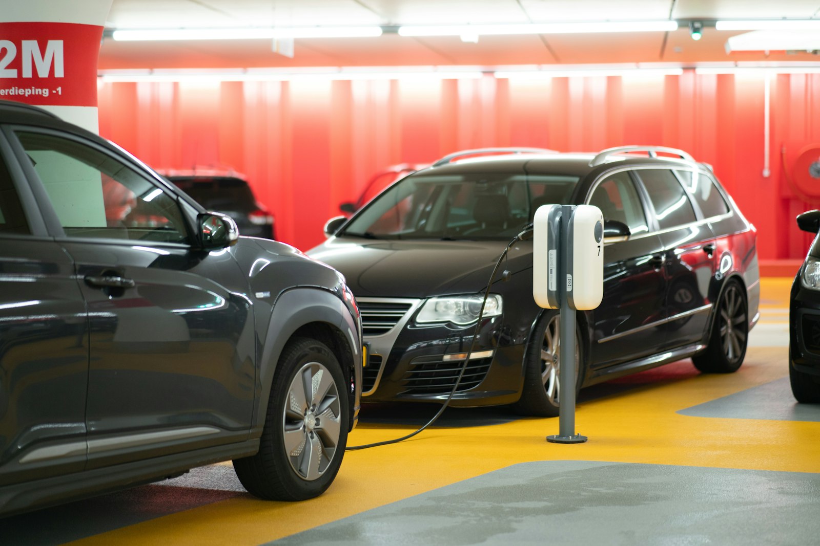 Vehículos eléctricos conectados a cargadores en un estacionamiento