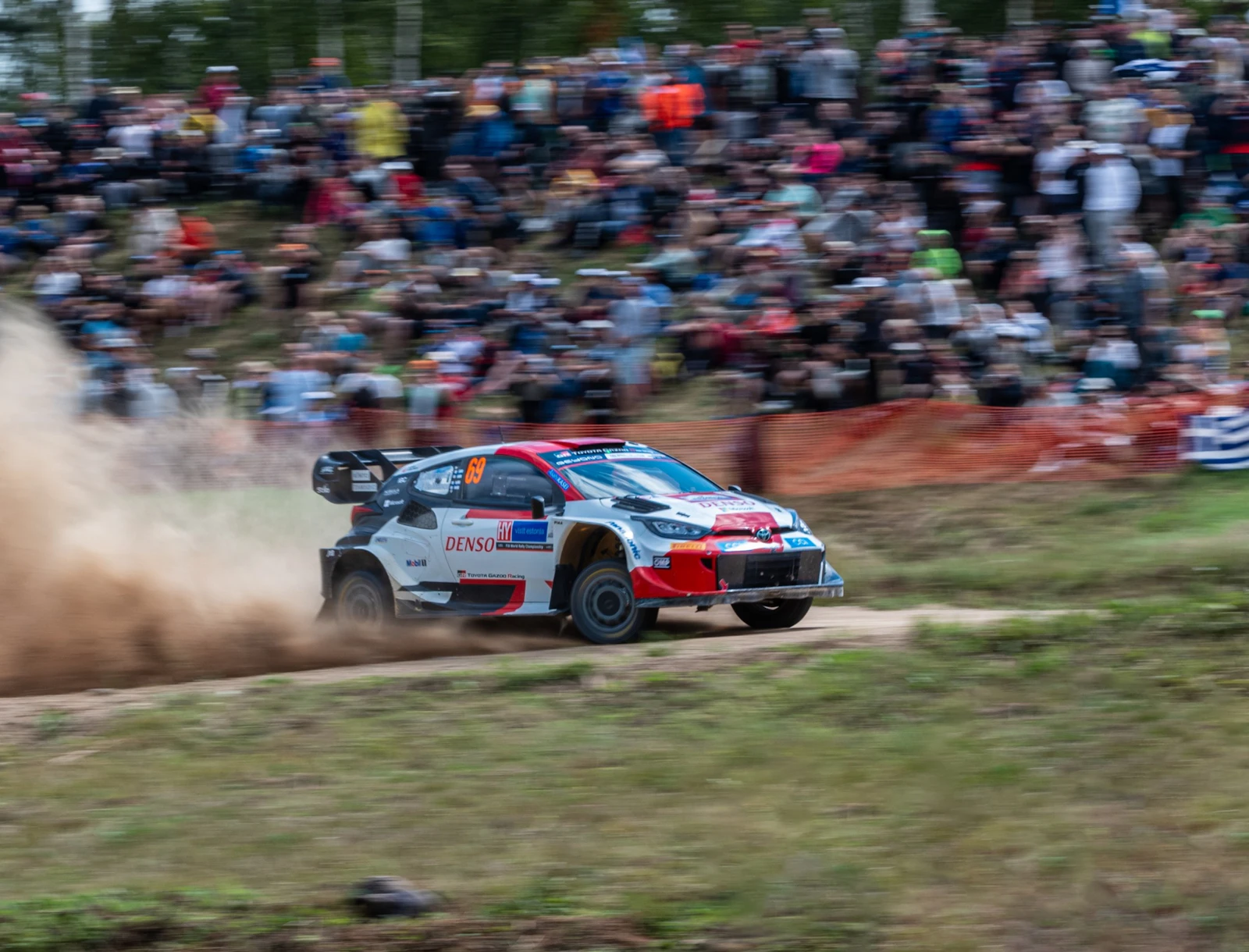 Automóvil de rally sobre un camino de tierra frente a espectadores