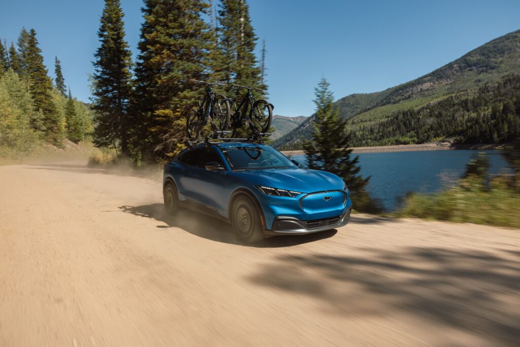 Ford Mustang Mach-E Trail 2027 circulando por camino de tierra con bicicletas en el techo
